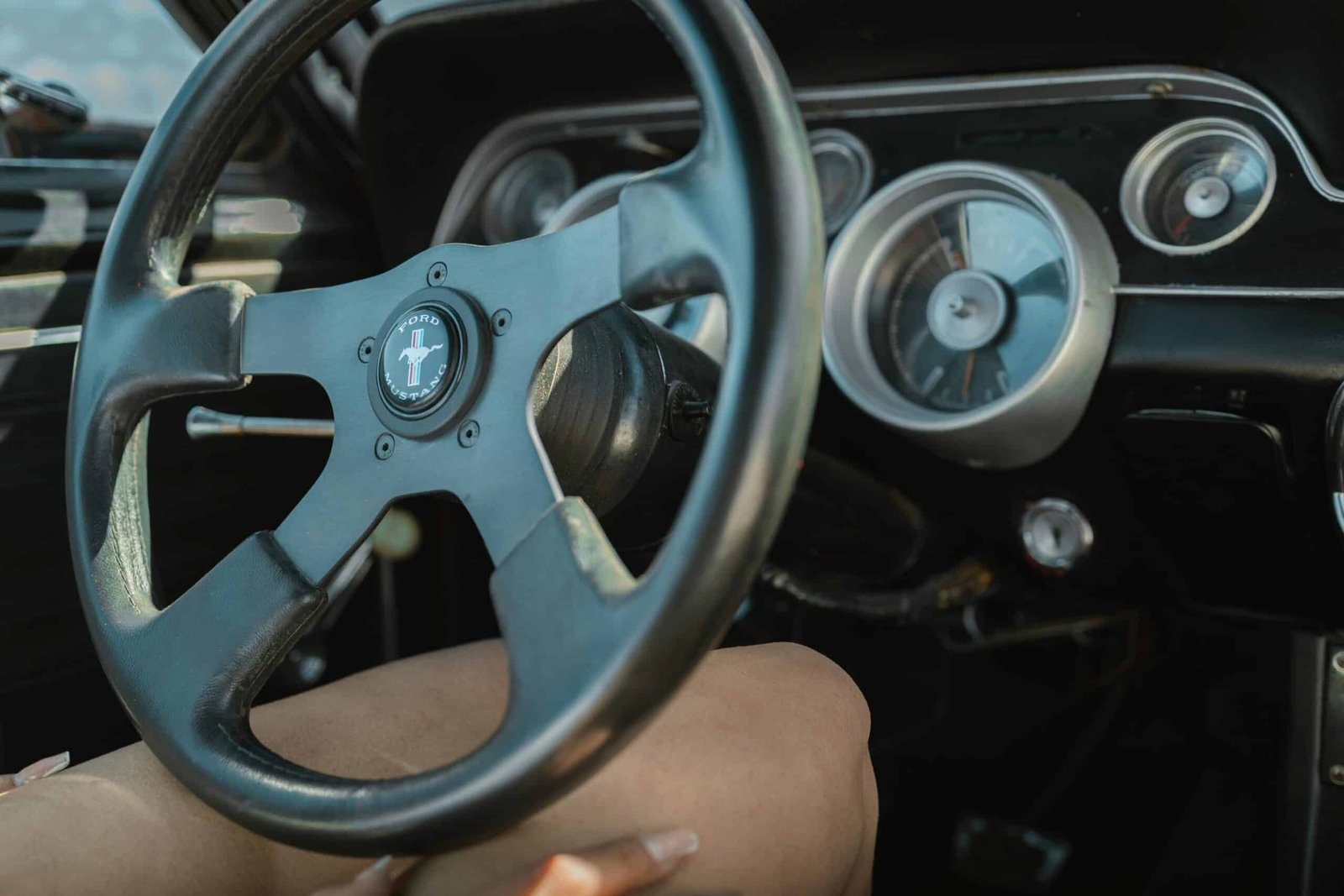 Cerrar-up of a vintage Ford Mustang steering wheel and dashboard showcasing retro car design.